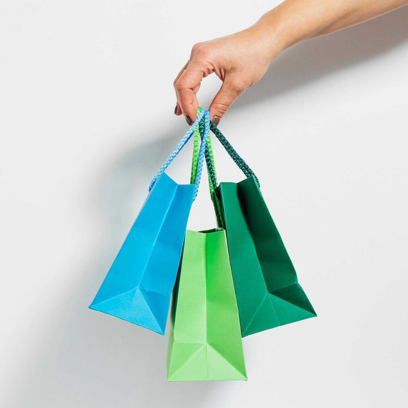A hand holding vibrant paper shopping bags, perfect for retail and sales themes.
